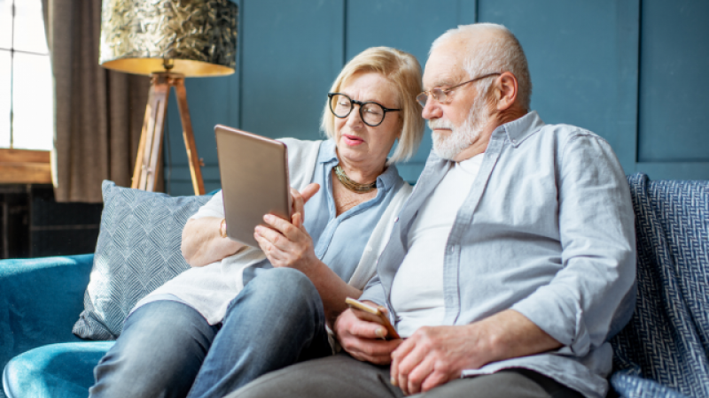 Photo of older man and woman smiling and using a tablet