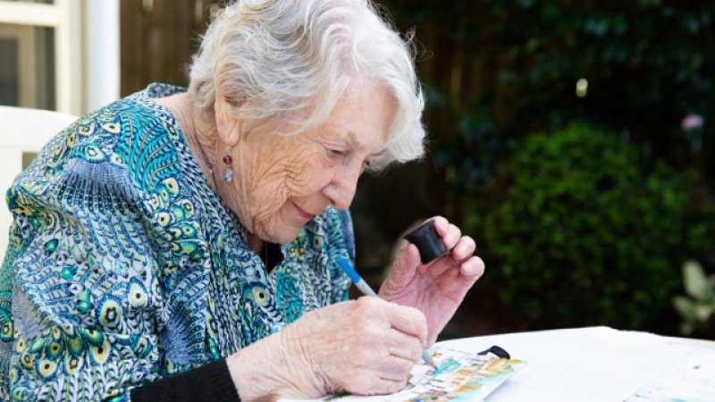 Photo of an older lady using a magnifier to read a small book